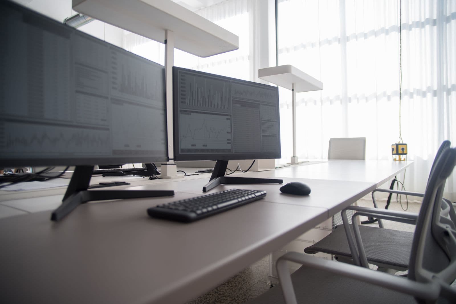 Moderner Arbeitsplatz: zwei Bildschirme mit Auswertungen in einem hellen Büro